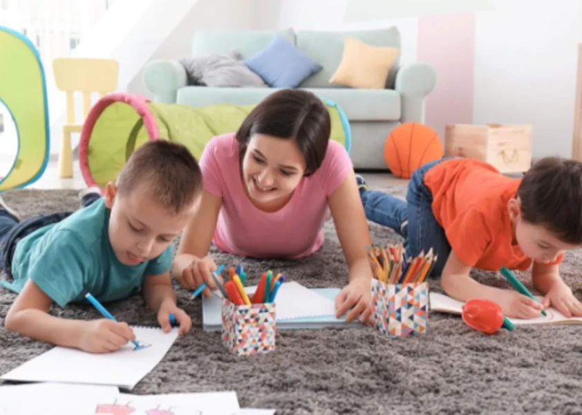 1 gardienne et 2 enfants font des dessins