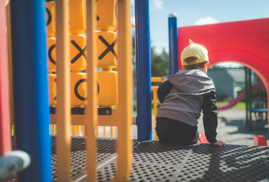 jeune enfant assis de dos dans une structure de jeux